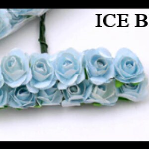 Puede incluir: Un grupo de rosas de papel azul claro con tallos verdes. Las rosas est&aacute;n dispuestas en fila y todas miran en la misma direcci&oacute;n. El texto "ICE BLUE" est&aacute; escrito en letras negras en la parte superior de la imagen.