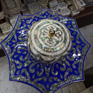 Könnte beinhalten: Ein dekoratives sternförmiges Tablett mit einem runden Behälter mit Deckel in der Mitte. Das Set besticht durch ein leuchtend blaues Finish mit aufwendigen, eingelegten, irisierenden Perlmutt-Mosaikmustern und einem kleinen, polierten goldfarbenen Knopf auf dem Deckel.