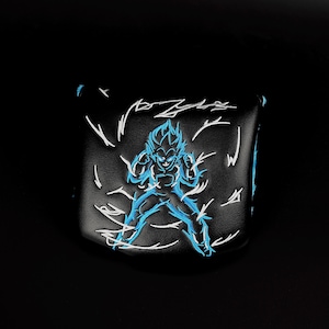 Puede incluir: Funda negra para la cabeza del palo de golf con un diseño bordado en azul de un personaje con pelo puntiagudo y una postura decidida. Rayos blancos rodean al personaje, creando un efecto dinámico. Hecha de un material oscuro y liso.