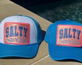 May include: Two blue and white trucker hats with a pink and gold patch that says "Salty" on each hat.