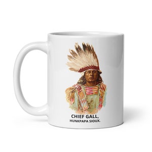 Peut inclure: Mug en céramique blanche avec une illustration en couleur de Chief Gall, Hunkpapa Sioux, portant une coiffe à plumes. Le mug a une légende en texte noir qui dit "Chief Gall, Hunkpapa Sioux."