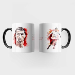 May include: White ceramic mug with a black handle. The mug features a watercolour illustration of Cristiano Ronaldo, a famous football player. The text "Cristiano Ronaldo" is printed on the mug.