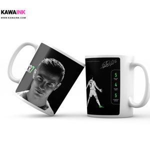May include: Two white ceramic mugs with black and white images of a football player. One mug features a close-up of Cristiano Ronaldo with the text "CR7". The other mug features a player in action with the text "Ballon d'Or" and a list of awards won.
