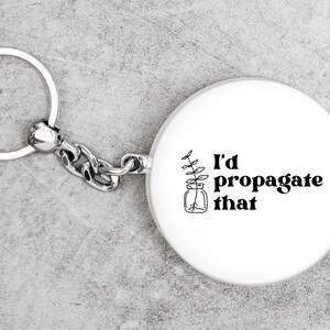 Peut inclure: Un porte-cl&eacute;s rond blanc avec une illustration noir et blanc d'une plante dans un bocal et le texte "I'd propagate that".