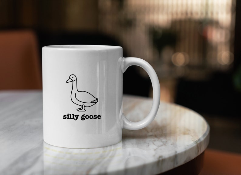 May include: White ceramic mug with a black line drawing of a goose and the text "silly goose" printed on the front.
