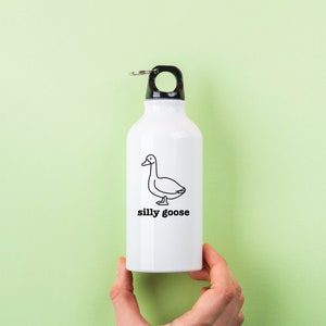May include: White water bottle with a black lid and a black and white illustration of a goose with the text "silly goose" printed on the front.