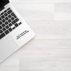 K&ouml;nnte beinhalten: Ein wei&szlig;er Laptop mit einer schwarzen Tastatur und einem Aufkleber auf dem Trackpad, der "Schau mich nicht an, ich habe nicht f&uuml;r ihn gestimmt" sagt.