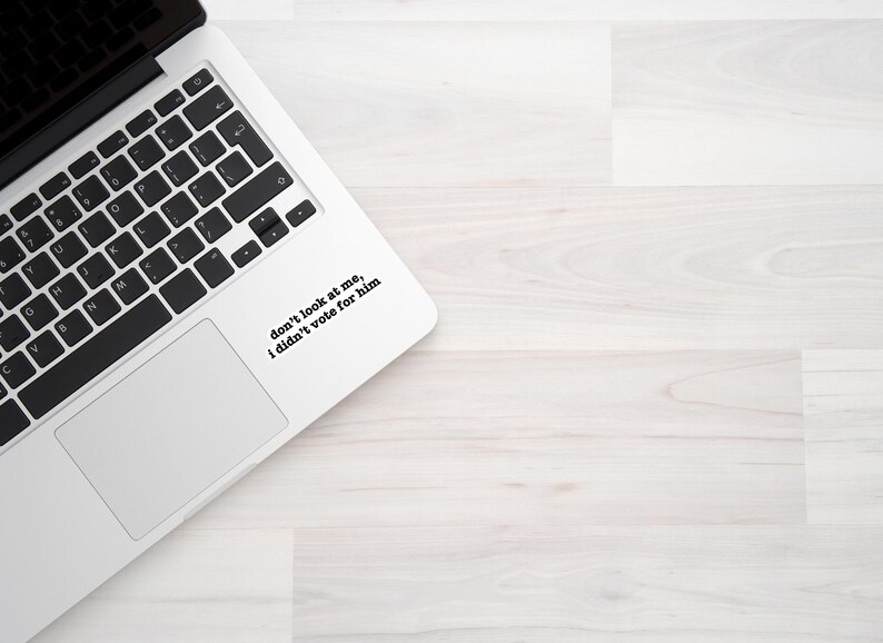 K&ouml;nnte beinhalten: Ein wei&szlig;er Laptop mit einer schwarzen Tastatur und einem Aufkleber auf dem Trackpad, der "Schau mich nicht an, ich habe nicht f&uuml;r ihn gestimmt" sagt.