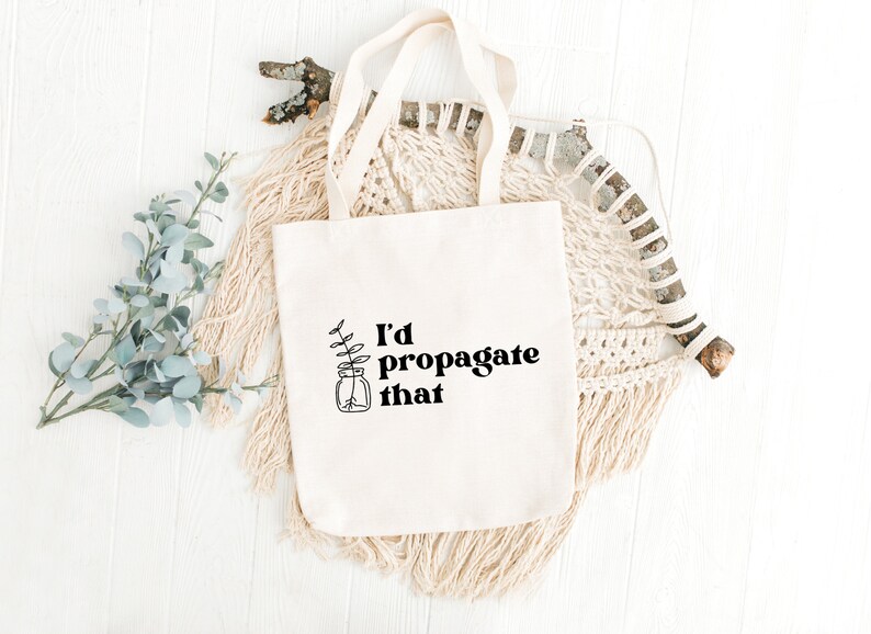 Peut inclure: Un sac fourre-tout en toile blanche avec le texte "I'd propagate that" et un dessin simple d'une plante dans un bocal.