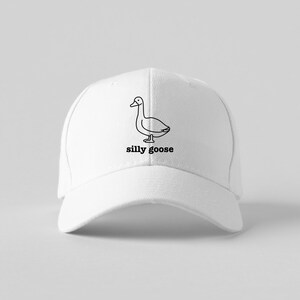 May include: White baseball cap with a black line drawing of a goose and the text "silly goose" embroidered on the front.