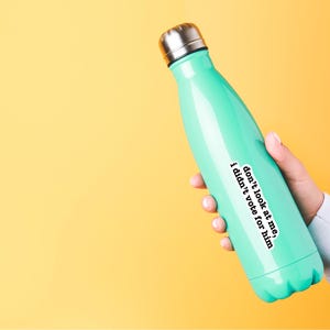 K&ouml;nnte beinhalten: Eine t&uuml;rkisfarbene wiederverwendbare Wasserflasche mit einem wei&szlig;en Aufkleber, auf dem steht: "Schau mich nicht an, ich habe nicht f&uuml;r ihn gestimmt"
