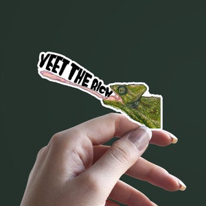 以下が含まれることがあります： 「YEET THE RICH」と書かれた、ピンクの舌を出した緑色のカメレオンのステッカーです。