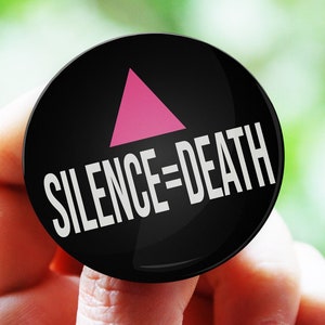 以下が含まれることがあります： ピンクの三角形と白い文字「SILENCE=DEATH」が書かれた黒いボタン