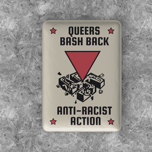 Könnte beinhalten: Ein weißer quadratischer Knopf mit roten Sternen und schwarzem Text, der "Queers Bash Back" und "Anti-Racist Action" lautet. Ein rosa Dreieck mit einem schwarzen Symbol im Inneren befindet sich in der Mitte des Knopfes.