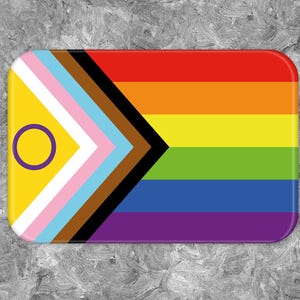 Könnte beinhalten: Ein rechteckiger Aufkleber mit einem Regenbogen-Pride-Flaggen-Design. Die Flagge hat eine schwarze und braune Spitze auf der linken Seite, gefolgt von einem rosa, hellblauen und weißen Streifen. Die rechte Seite der Flagge zeigt die traditionellen Regenbogenfarben: Rot, Orange, Gelb, Grün, Blau, Indigo und Violett. Ein gelber Kreis mit einem violetten Ring befindet sich in der oberen linken Ecke.