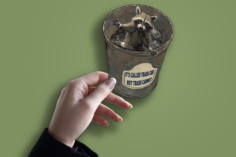 May include: A raccoon sitting in a metal trash can with the text "IT'S CALLED TRASH CAN NOT TRASH CANNOT" on the side.