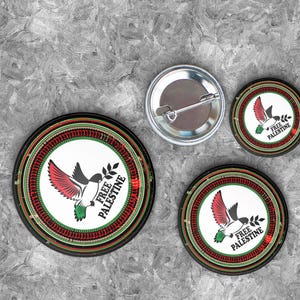 Puede incluir: Un conjunto de botones redondos y un botón de alfiler. Los botones presentan un pájaro con alas rojas y verdes que lleva una rama de olivo, con el texto "FREE PALESTINE". El botón de alfiler es plateado.