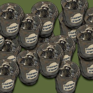 May include: A stack of round stickers featuring a raccoon in a bin with the text "It's called trash can, not trash cannot".