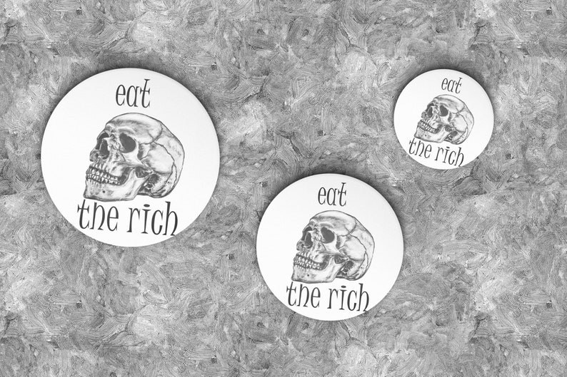 May include: Three white round buttons with a black skull and the text "eat the rich" on each.