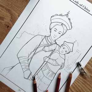 May include: A black and white line drawing of Our Lady of China holding a child, with the title at the top. Several coloured pencils and a pen are on the wooden surface. The image is ready to be coloured.