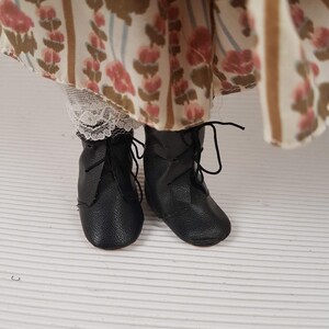 Puede incluir: Un par de botas de cuero negro con cordones y punta redonda. Las botas est&aacute;n gastadas y tienen un aspecto vintage.