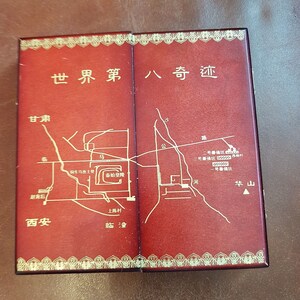 May include: A red leather-bound box with gold accents and a map of the Terracotta Army in Xi'an, China. The box has the text "World Eighth Wonder" in Chinese characters on the front.