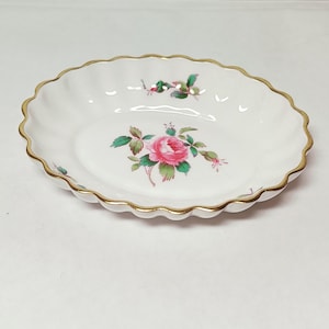 Könnte beinhalten: Eine weiße Porzellanschale mit goldfarbenem Rand und einem rosafarbenen Rosenblütenmuster.