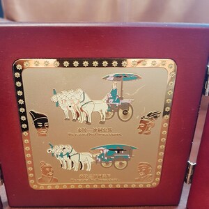 May include: A wooden plaque with a gold border and a gold image of a chariot pulled by horses. The plaque has the text "The restored No.1 bronze chariot" and "The restored No.2 bronze chariot" in English and Chinese.