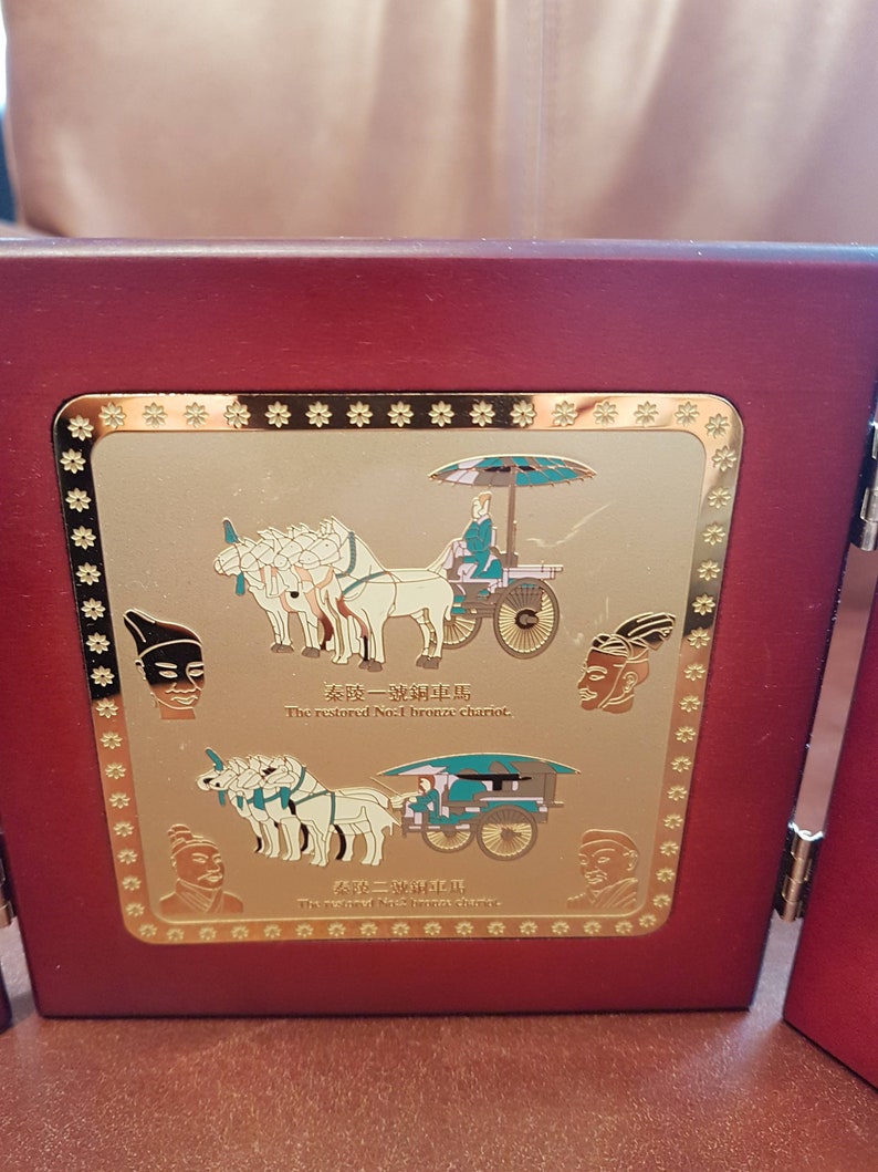 May include: A wooden plaque with a gold border and a gold image of a chariot pulled by horses. The plaque has the text "The restored No.1 bronze chariot" and "The restored No.2 bronze chariot" in English and Chinese.