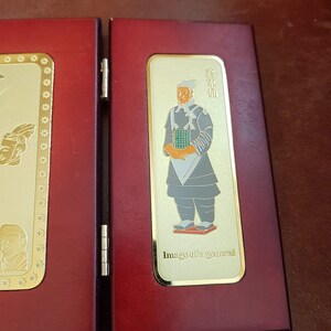 May include: A red wooden box with a gold-colored image of a general in traditional clothing. The image is framed with a gold border and includes the text "Image of a general".