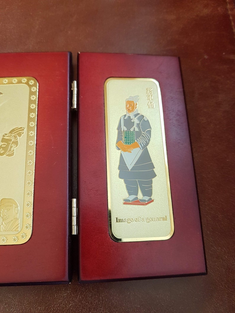 May include: A red wooden box with a gold-colored image of a general in traditional clothing. The image is framed with a gold border and includes the text "Image of a general".