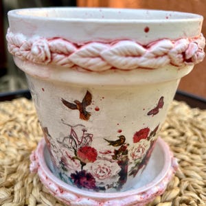 Maceta de arcilla con diseño floral estilo shabby chic y platillo.