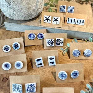 Op de afbeelding: Assortiment van keramische oorbellen met blauwe en witte ontwerpen. De oorbellen hebben verschillende maritieme thema's, waaronder schelpen, zeesterren, vissen en krabben.