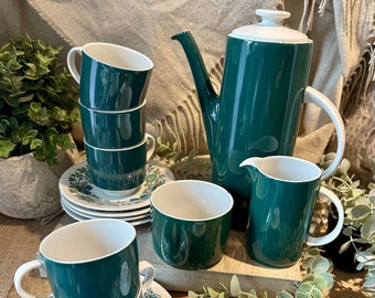 May include: A vintage green and white tea set with floral patterns on the saucers. The set includes a teapot, creamer, sugar bowl, and four cups.
