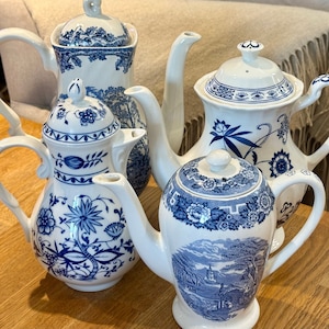 May include: Four blue and white porcelain teapots with floral designs. The teapots are arranged on a wooden surface.