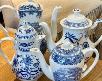 May include: Four blue and white porcelain teapots with floral designs. The teapots are arranged on a wooden surface.