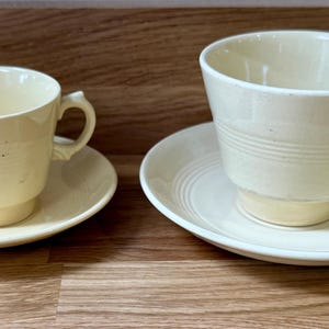 Può includere: Due tazze da tè e piattini color crema. Le tazze hanno una forma svasata con manico e poggiano su piattini rotondi abbinati. Il set è in ceramica e ha un design semplice ed elegante.