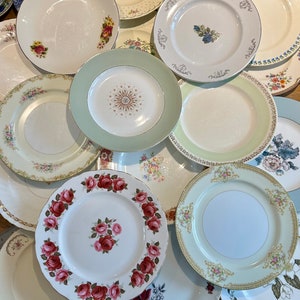 May include: A selection of vintage ceramic plates with floral patterns. The plates display a range of colours, including white, green, and pink, with gold edging. Some plates feature rose designs, while others have delicate floral arrangements. Various sizes and styles are visible.