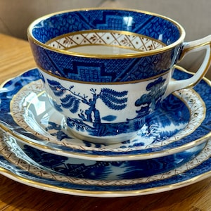 Può includere: Servizio da tè in porcellana blu e bianca con finiture dorate. La tazza presenta un motivo blu dettagliato sul bordo e un design scenografico sul corpo. Il set include due piatti aggiuntivi abbinati.