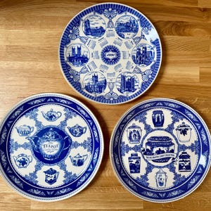 Puede incluir: Tres platos decorativos azules y blancos. Uno presenta ilustraciones de edificios y el año 1990. El segundo tiene teteras y el texto "The Tea Pot Collection". El tercero tiene tarros y el texto "The Decorative Candy Collection".
