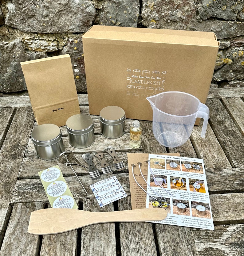 May include: Candle making kit with a brown cardboard box, soy wax bag, metal tins, a measuring jug, and a wooden spatula. The box reads "Make Your Own Soy Wax Candles Kit". Includes instructions, wicks, and fragrance oil.