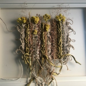 K&ouml;nnte beinhalten: Ein gerahmter Wandbehang mit einer gewebten Tapisserie mit getrockneten Blumen und Gr&auml;sern in Braun-, Beige- und Gelbt&ouml;nen.