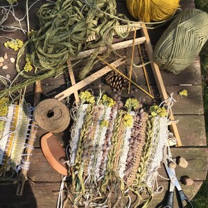 K&ouml;nnte beinhalten: Nahaufnahme einer gewebten Wandbeh&auml;nge aus Naturfasern und getrockneten Blumen. Die Beh&auml;nge befindet sich auf einem Holzwebstuhl mit gr&uuml;nem Garn und Schnur.