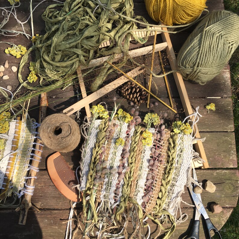 K&ouml;nnte beinhalten: Nahaufnahme einer gewebten Wandbeh&auml;nge aus Naturfasern und getrockneten Blumen. Die Beh&auml;nge befindet sich auf einem Holzwebstuhl mit gr&uuml;nem Garn und Schnur.
