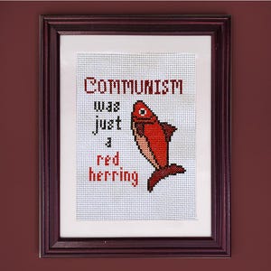 May include: A framed cross-stitch design with a red fish and the text "Communism was just a red herring."