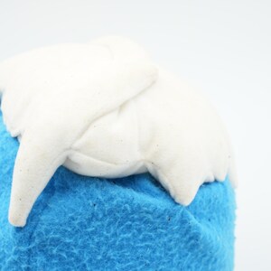 Puede incluir: Un juguete de peluche blanco con forma de monta&ntilde;a con una base de felpa azul.