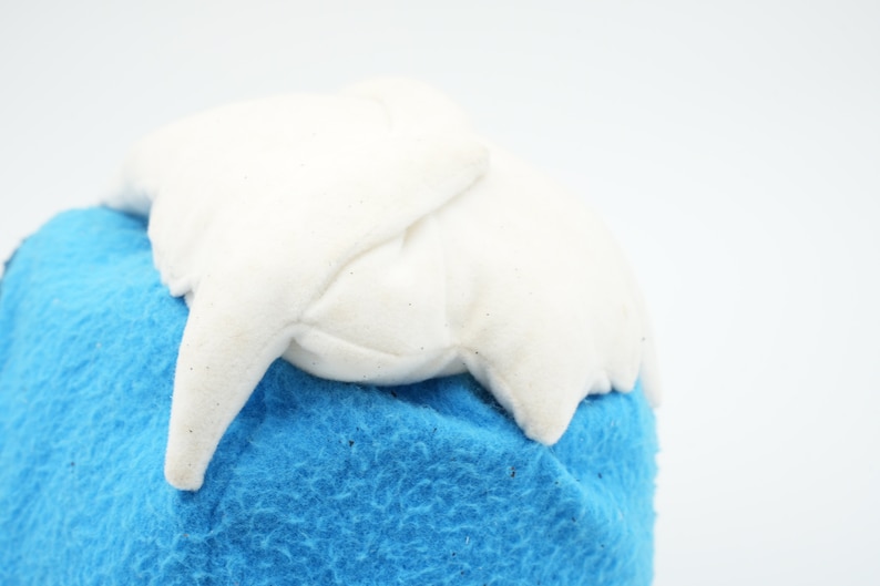 Puede incluir: Un juguete de peluche blanco con forma de monta&ntilde;a con una base de felpa azul.