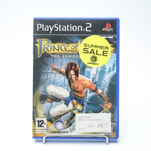 Op de afbeelding: PlayStation 2 game case voor "Prince of Persia: The Sands of Time". De cover toont een man in actie, met een stadsgezicht op de achtergrond. Een gele "Summer Sale" sticker is aanwezig.