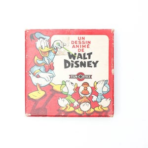 May include: A red box with a cartoon image of Donald Duck and three ducklings. The box reads "Un dessin anime de Walt Disney Film-Office".