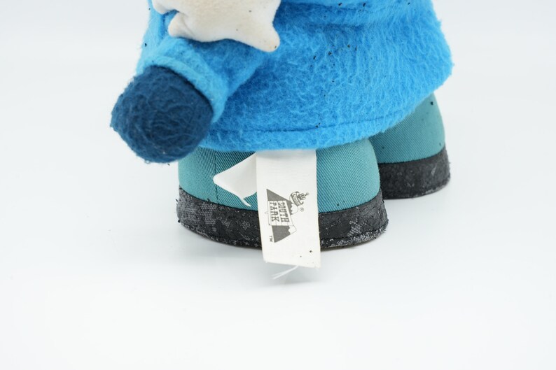 Puede incluir: Peluche azul y turquesa con una etiqueta blanca que dice "South Park" sobre un fondo blanco.